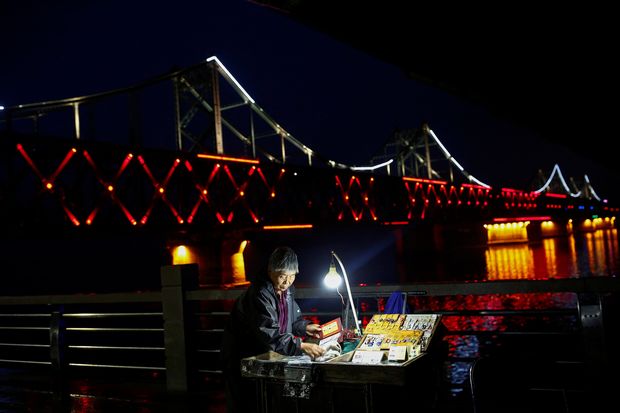 A woman sells cigarettes in front of the bridge across Yalu River that connects China's Dandong, Liaoning province, and North Korea's Sinuiju September 10, 2016. REUTERS/Thomas Peter ORG XMIT: TPE33