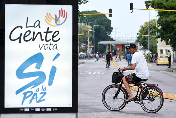 Cartaz pede voto a favor do acordo de paz em plebiscito; ao fundo, morador de Cartagena