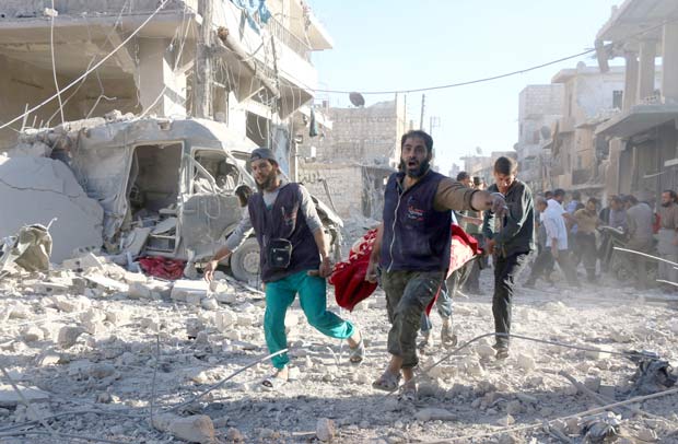 Voluntrios srios carregam pessoa ferida aps bombardeio em bairro rebelde de Aleppo nesta sexta (30)