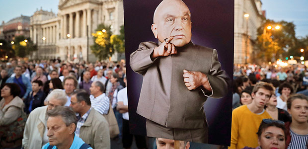 A man holds a banner depicting Hungarian Premier Viktor Orban, the reads 