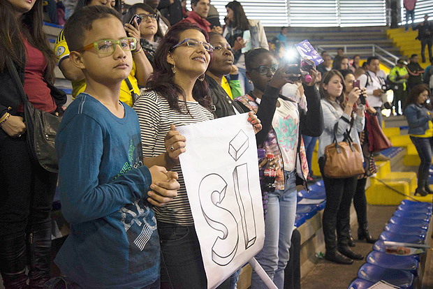 Supporters of Colombian President Juan Manuel Santos hold a sign reading "Yes" ahead of Sunday referendum during a volleyball match between Colombian and Rwanda in Bogota, Colombia, on October 1, 2016. Colombians will vote a referendum Sunday on whether to ratify a historic peace accord to end the 52-year war between the state and the communist FARC rebels. The accord will effectively end what is seen as the last major armed conflict in the Western Hemisphere. The war has killed hundreds of thousands of people and displaced millions. / AFP PHOTO / Diana SANCHEZ ORG XMIT: DSM