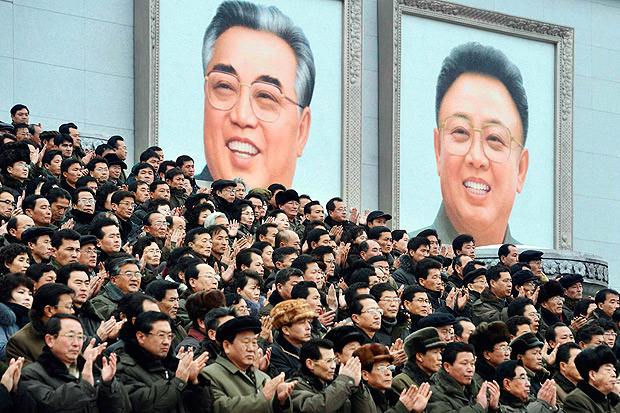 Pblico aplaude em frente s imagens de Kim Il-sung (esq.) e Kim Jong-il