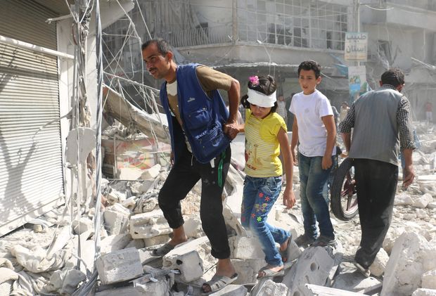 Moradores caminham por escombros no distrito de Fardous, em Aleppo, atingido por bombardeios nesta quarta (12)