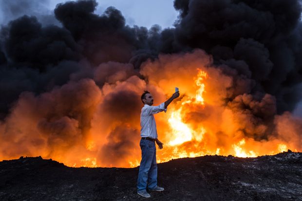 Em meio a ofensiva iraquiana, homem tira selfie em frente a incndio de um campo de petrleo, a 60 km de Mossul