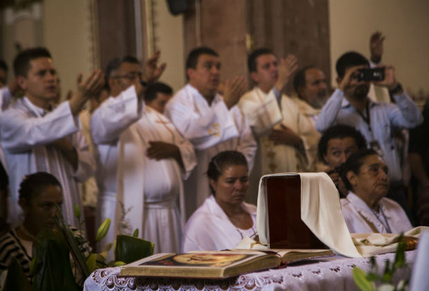 Parishioners and friends show their respect to the urn with the ashes of Catholic priest Jose Alfredo Lopez in the Santisima Trinidad church in the Janamuato community, Michocan state, Mexico on September 26, 2016. The bullet-riddled body of a priest who had disappeared in western Mexico has been found, authorities said Sunday, making him the third cleric murdered this week in the country. Lopez, who had vanished on Monday from his parish house in Janamuato, a village in the troubled state of Michoacan, was found on Saturday night on a parcel of land.