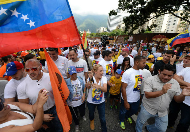 Lilian Tintori, wife of prominent jailed opposition leader Leopoldo Lopez, waves a Venezuelan national flag as she marches against the government of President Nicolas Maduro in the streets of Caracas on October 26, 2016. Venezuela's political rivals are set to engage in a volatile test of strength on Wednesday, with the opposition vowing mass street protests as President Nicolas Maduro resists efforts to drive him from power. The socialist president and center-right-dominated opposition accuse each other of mounting a "coup" in a volatile country rich in oil but short of food.