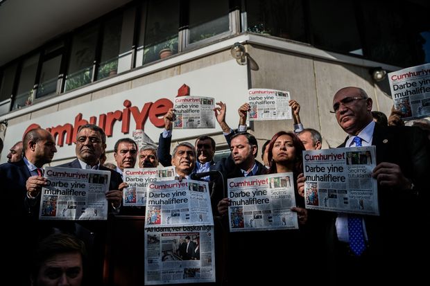 Em frente  sede do Cumhuriyet, membros da oposio turca seguram cpias do jornal onde se l: 'golpe contra a oposio