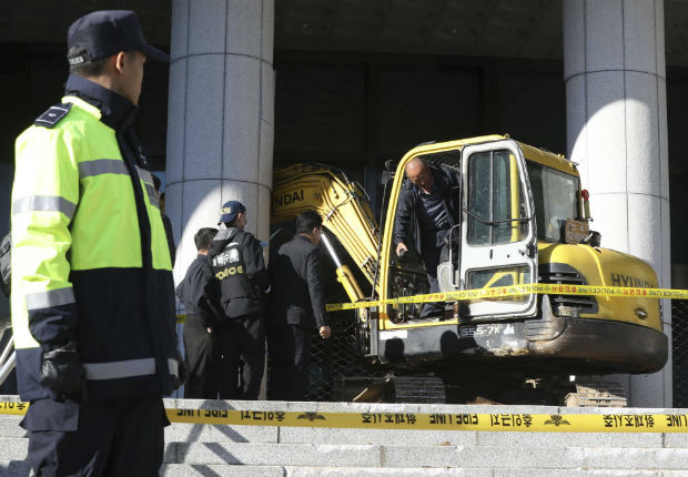 Police officers examine an excavator after a man rammed into a gate near a Seoul prosecutors' office in Seoul, South Korea, Tuesday, Nov. 1, 2016. Police detained the man. The man later told investigators he tried to meet and help the woman with her death because she told reporters she deserves death. (Kim Do-hoon/Yonhap via AP) ORG XMIT: SEL801