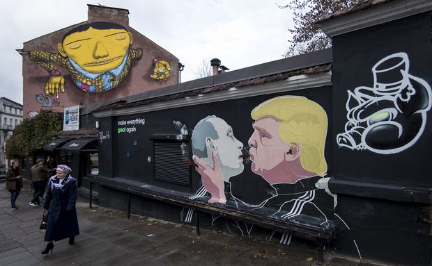 A woman walks past a graffiti artwork depicting Russian President Vladimir Putin, left, and Republican presidential candidate Donald Trump, on the walls of a bar in the old town in Vilnius, Lithuania, Sunday, Oct. 30, 2016. (AP Photo/Mindaugas Kulbis) ORG XMIT: XMK101