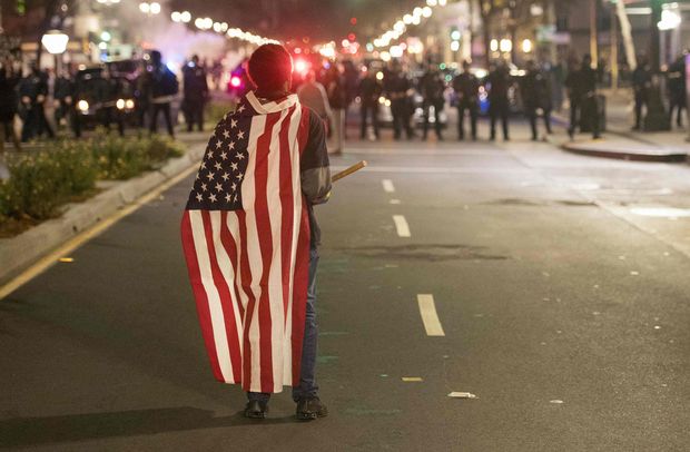 Manifestante com bandeira americana durante protesto anti-Trump em Oakland, na Califrnia