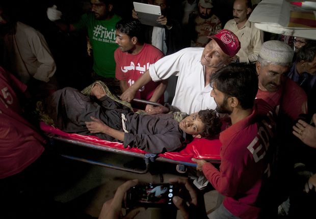 Pessoas levam ferido em ataque no santurio de Shah Noorani, no Paquisto