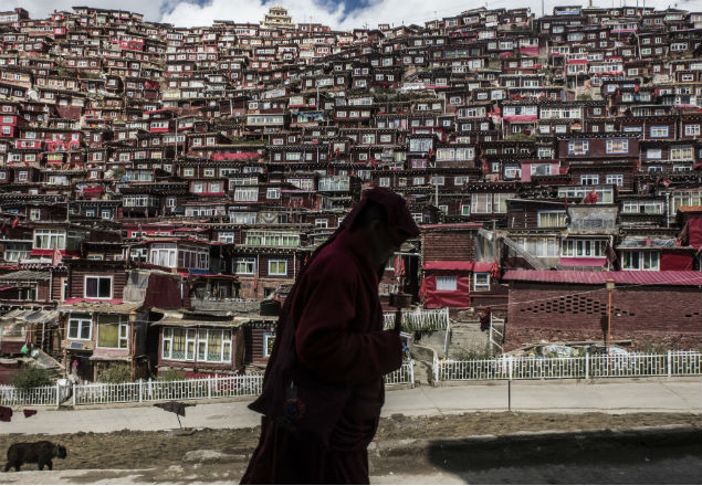 A Buddhist nun with a prayer wheel in Larung Gar, China, Oct. 8, 2016. In Larung Gar, the world’s largest Buddhist institute, demolition teams are cutting through an extraordinary vista of hand-built red dwellings. (Gilles Sabrie/The New York Times)