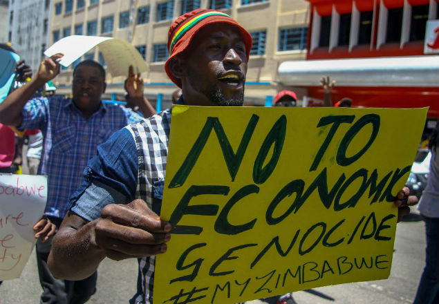 A protester holds a sign during a demonstration by opposition parties against the introduction of bond notes as a currency in Harare on November 30 2016. A token currency issued in Zimbabwe this week to ease critical cash shortages has brought little relief as desperate customers queue for hours to withdraw money while some traders reject the new notes. The central bank on November 28, 2016 issued $10 million in US dollar-equivalent 