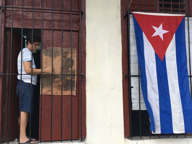 Mulher cola foto de Fidel na porta de casa, em Cienfuegos, Cuba