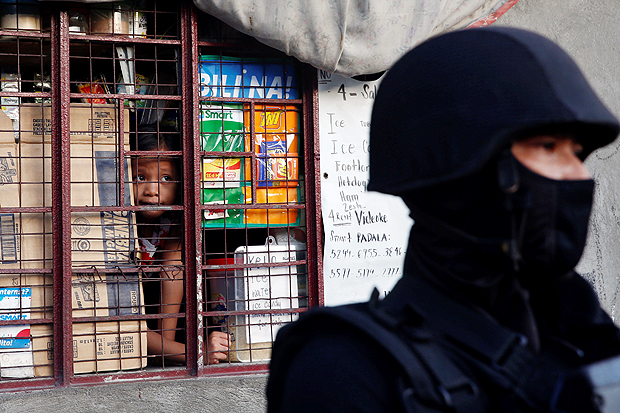 Homem e criana olhar por uma janela gradeada, de dentro de um pequeno mercado, um policial mascarado que faz operao na rua