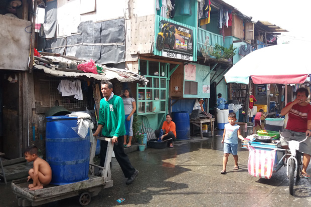 Menino toma banho e mulher lava roupa em favela na região de Tondo,, uma das com mais vítimas na guerra do presidente Duterte contra as drogas nas Filipinas