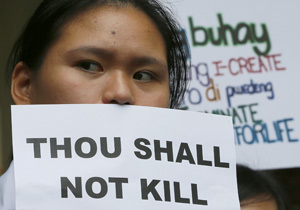 A students of St. Paul's University, a Roman Catholic university, displays her message as they come out from their campus to protest the killings being perpetrated in the unrelenting 