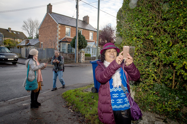 Chinese tourists take pictures in Kidlington, England Nov. 17, 2016. The rather ordinary village has found itself a popular stop for Chinese visitors who snap photographs of their simple homes and streets. (Elizabeth Dalziel/The New York Times) - XNYT51