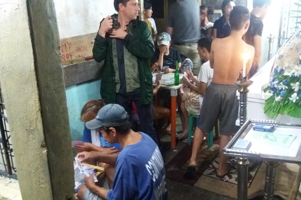 Durante velrio em Tondo, moradores jogam baralho para arrecadar dinheiro para pagar o funeral.