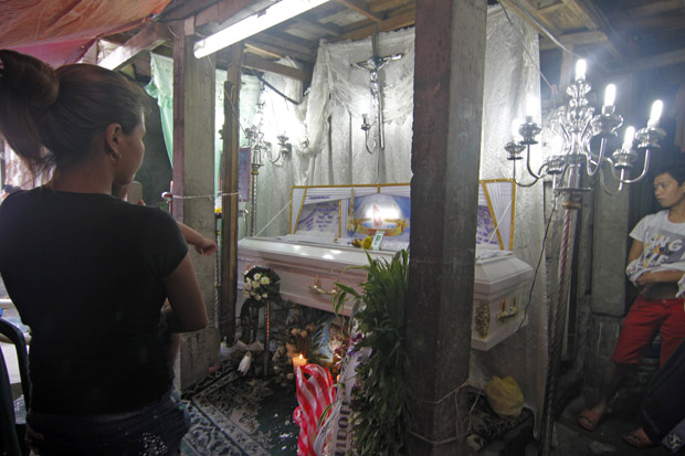 Viva segura um de seus dois filhos, de um e dois anos, no velrio de Michael Acuna, 25, morto por vigilantes quando reparava uma motocicleta na rua Batangas, na regio de Tondo, uma das mais pobres de Manila.