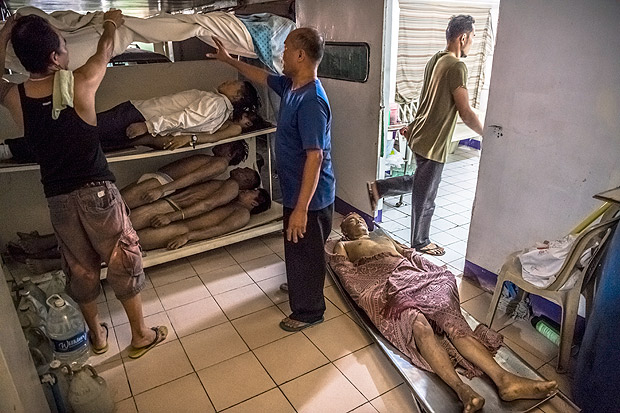 Bodies stacked up at a funeral parlor as the families of victims like Danilo Deparine, whose body lay on a metal stretcher on the floor, struggle to pay for burial, in Manila, Philippines, Oct. 11, 2016. A bloody and chaotic campaign against drugs that President Rodrigo Duterte began when he took office on June 30 has seen about 2,000 people slain at the hands of the police alone. (Daniel Berehulak/The New York Times)