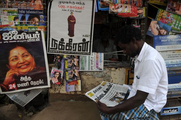  A Indian reads a newspaper covering the funeral of former Tamil Nadu Chief Minister Jayalalithaa Jayaram in Chennai on December 7, 2016. Hundreds of thousands of mourners paid an emotional final farewell December 6 to Indian politician Jayalalithaa Jayaram as the former movie star who enjoyed god-like status was buried alongside her on-screen lover. A day after the 68-year-old died following a massive weekend cardiac arrest, huge crowds lined the streets of Chennai as Jayalalithaa's coffin was taken to its final resting place in India's main southern city. / AFP PHOTO / ARUN SANKAR ORG XMIT: ASK2666