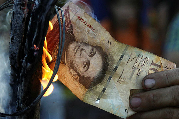 A man burns a 100-bolivar bill during a protest in El Pinal, Venezuela December 16, 2016. REUTERS/Carlos Eduardo Ramirez ORG XMIT: VEN208