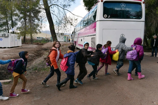 Crianas do campo de refugiados de Ritsona, na Grcia, formam fila para pegar o nibus para a escola