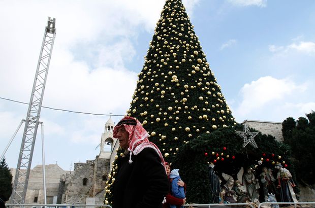 Palestino passa em frente à árvore de Natal perto da igreja na Natividade, em Belém, na Cisjordânia
