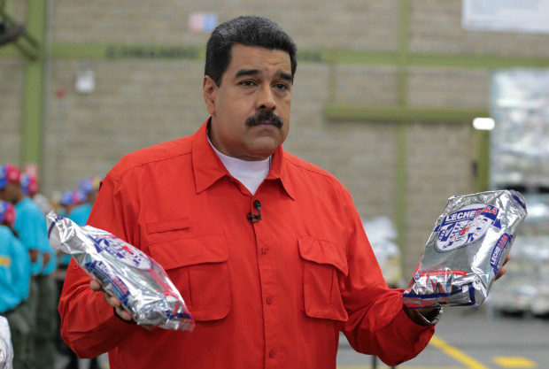 O presidente da Venezuela, Nicols Maduro, segura pacotes de leite em visita a depsito de comida