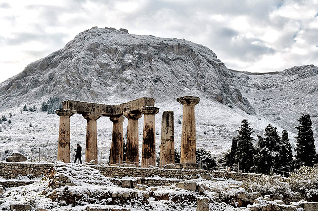 A person walks by the snow-covered temple of Apollon in Ancient Corinth on January 8, 2017. Greece experiences rare cold wave with low temperatures and snowfalls in many regions of the country. / AFP PHOTO / VALERIE GACHE ORG XMIT: LOU604