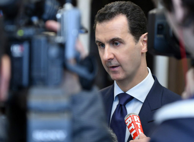 In this photo released Monday, Jan. 9, 2017 by the Syrian official news agency SANA, Syrian President Bashar Assad, left, speaks with French journalists in Damascus, Syria. Assad said in remarks published on Monday that he was prepared "to negotiate everything" at talks set to begin in later this month in Kazakhstan, seeking to cast himself as a peacemaker after his forces' recapture of Aleppo last month. Assad also defended his troops' deadly bombardment of eastern Aleppo. (SANA via AP) ORG XMIT: HAS103