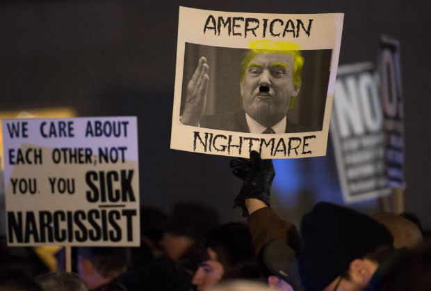 Manifestantes carregam cartazes contra Trump em protesto em frente a seu hotel, em Nova York