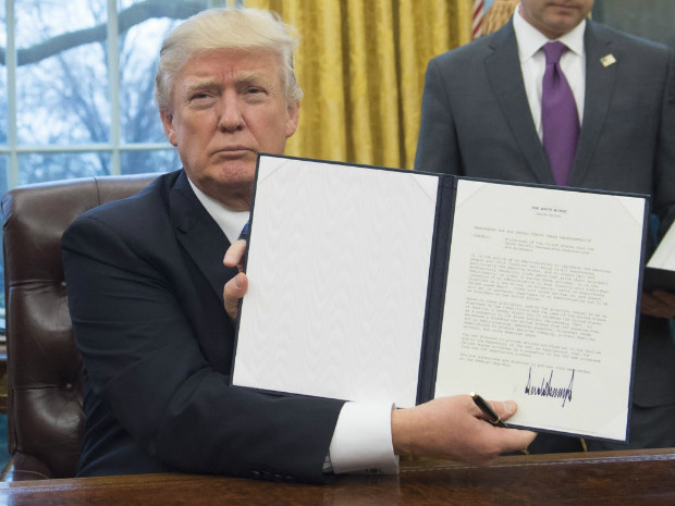 US President Donald Trump holds up an executive order withdrawing the US from the Trans-Pacific Partnership after signing it in the Oval Office of the White House in Washington, DC, January 23, 2017. Trump the decree Monday that effectively ends US participation in a sweeping trans-Pacific free trade agreement negotiated under former president Barack Obama. / AFP PHOTO / SAUL LOEB ORG XMIT: SAL001