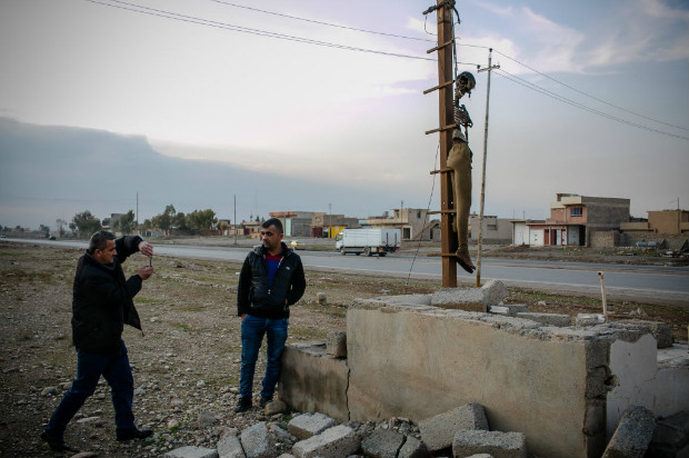 Moradores de Mossul tiram foto ao lado de cadver semidecomposto pendurado na entrada da cidade