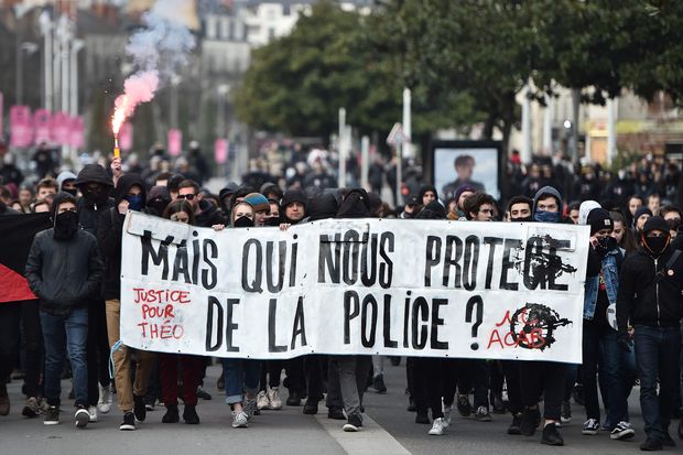 People hold a banner reading "Who protects us from the police?" as they demonstrate against police brutality on February 11, 2017 in Nantes, western France. Hundreds of people took part in the protest following the case of Theo, a 22-year-old black youth worker named as Theo, a talented footballer with no criminal record, who required surgery after his arrest on February 2, 2017 when he claims a police officer sodomized him with his baton. One officer has been charged with rape and three others with assault over the incident in the tough northeastern suburb of Aulnay-sous-Bois which has revived past controversies over alleged police brutality. / AFP PHOTO / JEAN-SEBASTIEN EVRARD ORG XMIT: 005
