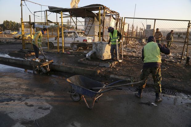 Funcionários da Prefeitura de Bagdá trabalham no local onde um carro-bomba explodiu nesta quinta