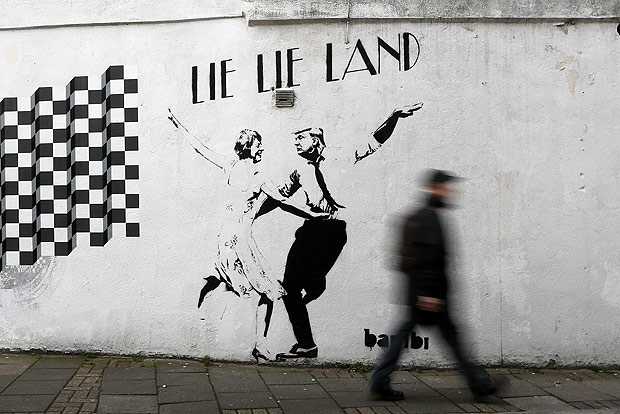 A pedestrian passes a new piece of art by street artist Bambi in London. in London, Thursday, Feb. 16, 2017. The work, entitled Lie Lie Land, features a dancing British Prime Minister Theresa May and President Donald Trump in the pose made famous by the movie La La Land. (AP Photo/Kirsty Wigglesworth) ORG XMIT: LKW109