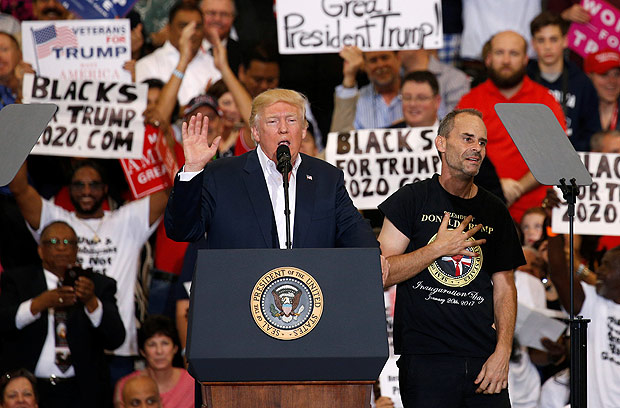 A supporter invited onstage by U.S. President Donald Trump puts his hand to his chest during a 