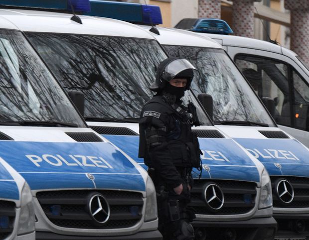 Policial de unidade especial próximo a carros da polícia durante operação em Frankfurt