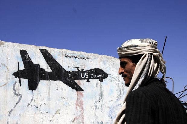 Iemenita caminha em frente a muro com pichao representando drone dos EUA na capital do pas, Sanaa