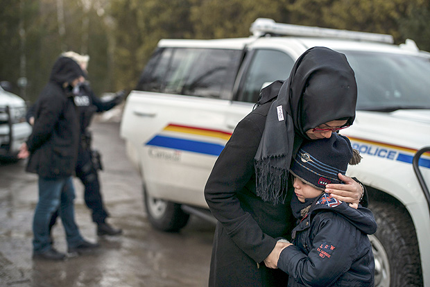 Mulher conforta o filho, enquanto o marido  algemado pela polcia por atravessar ilegalmente a fronteira