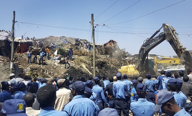 Police officers secure the perimeter at the scene of a garbage landslide, as excavators aid rescue efforts, on the outskirts of the capital Addis Ababa, Ethiopia Sunday, March 12, 2017. Officials and residents say more than a dozen people have been killed in a landslide at a massive garbage dump on the outskirts of Ethiopia's capital, and several dozen people are missing. (AP Photo/Elias Meseret) ORG XMIT: NAI101