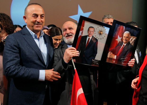 Turkish Foreign Minister Mevlut Cavusoglu poses with a supporter holding portraits of Turkish President Recep Tayyip Erdogan and Prime Minister Binali Yildirim (R) at the end of a political rally on Turkey's upcoming referendum, in Metz, France, March 12, 2017. REUTERS/Vincent Kessler ORG XMIT: VAK0