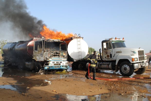A firefighter stands near a petrol tanker on fire following a suicide attack in Maiduguri on March 3, 2017. Multiple explosions rocked the outskirts of Nigeria's northeastern city of Maiduguri early Friday, killing three suicide bombers, the emergency service and police said. / AFP PHOTO / STRINGER ORG XMIT: NIGERIA02a