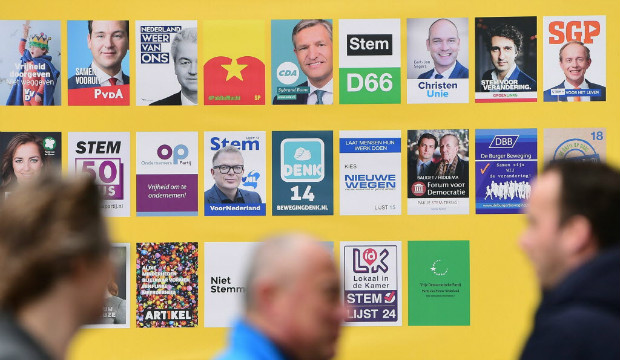 Pedestres de Haia passam por cartazes dos diferentes partidos que concorrem � elei��o na Holanda
