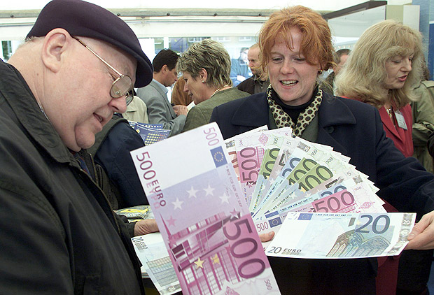 ORG XMIT: 480201_1.tif Alemes olham notas grandes de euros que fazem parte de campanha para popularizar as cdulas. Karl-Heinz Bannweg, left, looks on a oversized 500 euro notes given to him by Angela Joosten, right, in Freiburg, southern Germany, on Friday, Sept. 14, 2001. The German Federal Bank started an advertising campaign to make people more familiar with new currency which will be introduced on Jan. 1, 2002. (AP Photo/ Winfried Rothermel)