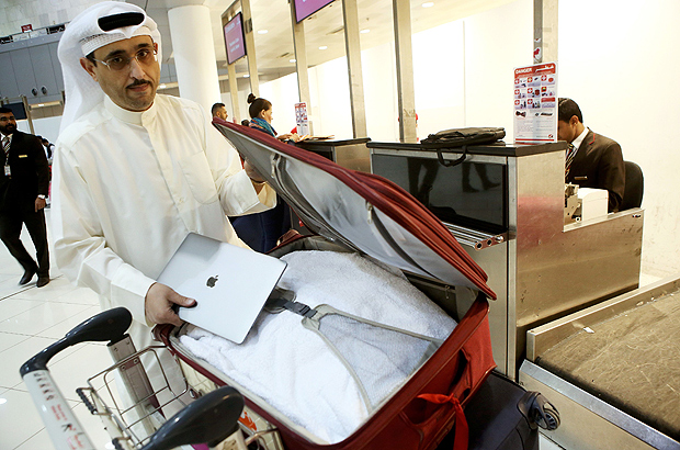 Kuwaiti social media activist Thamer al-Dakheel Bourashed puts his laptop inside his suitcase at Kuwait International Airport in Kuwait City before boarding a flight to the United States on March 23, 2017. Travellers across the Middle East have expressed frustration at a ban on large electronic devices for flights to the United States and Britain that has sparked confusion and speculation. From March 25, passengers on flights to the United States and Britain from major hubs in Turkey and the Arab world will have to check in any device larger than a smartphone, including laptops and tablets. / AFP PHOTO / Yasser Al-Zayyat