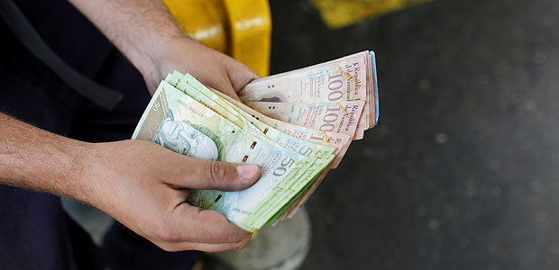 A worker counts Venezuelan bolivar notes at a gas station of Venezuelan state oil company PDVSA in Caracas, Venezuela March 21, 2017. REUTERS/Marco Bello ORG XMIT: GGGMAB107