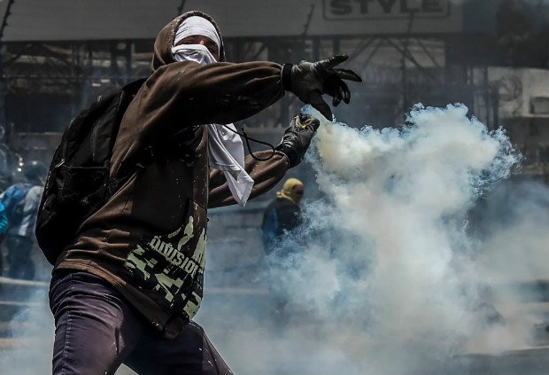 Manifestante atira de volta uma bomba de gs lacrimogneo atirada por policiais em Caracas